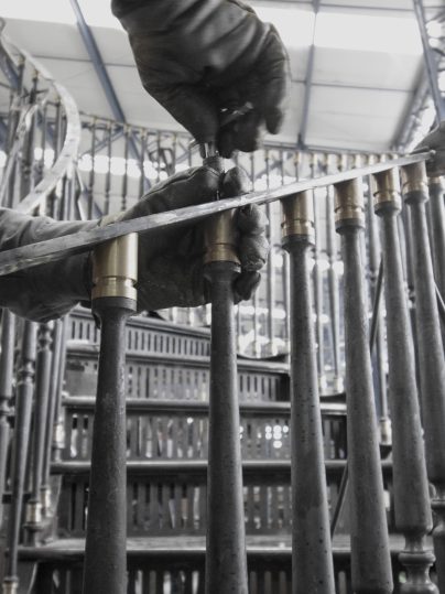 Artisan attaching the pickets and the bronze handrail to the steps